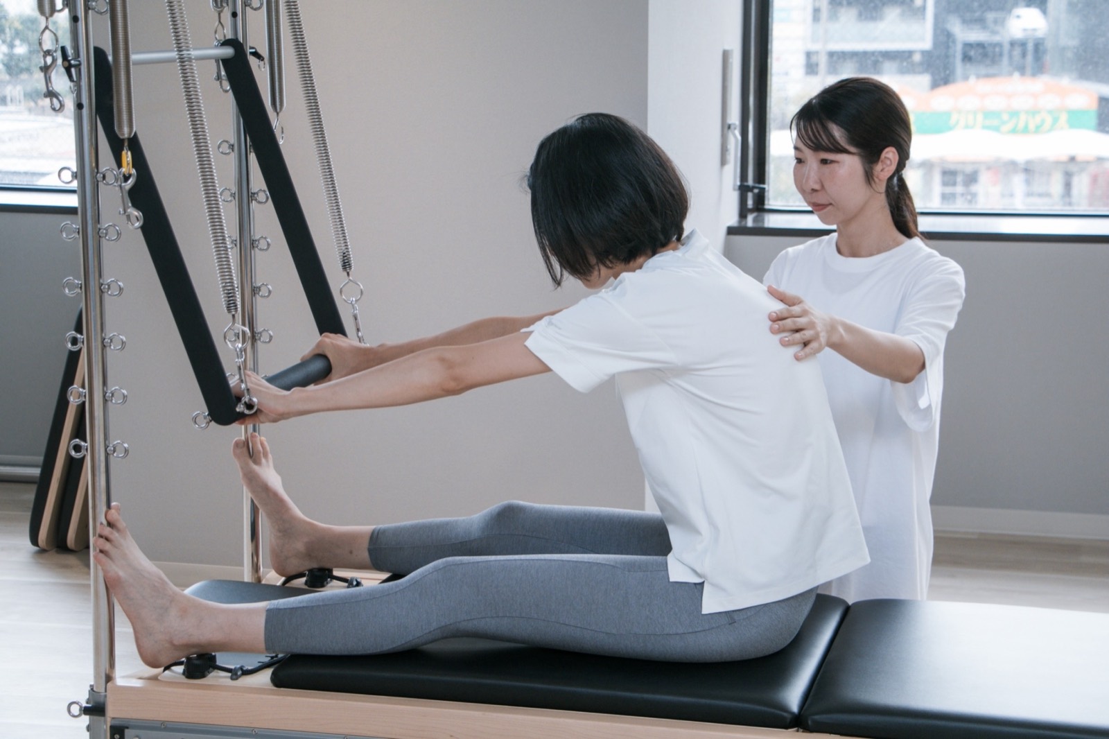 トレーナーが背中に手を添えて姿勢を確認する様子